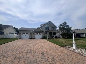 A two-story house with a brick driveway, two garage doors, and a front porch. - 12 Canary Dr. – Pilottown Village, Private Saltwater Pool, Minutes to Downtown Lewes & Lewes Beach (Lewes)