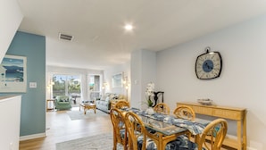 A dining area with a glass table, wicker chairs, and a clock on the wall.
