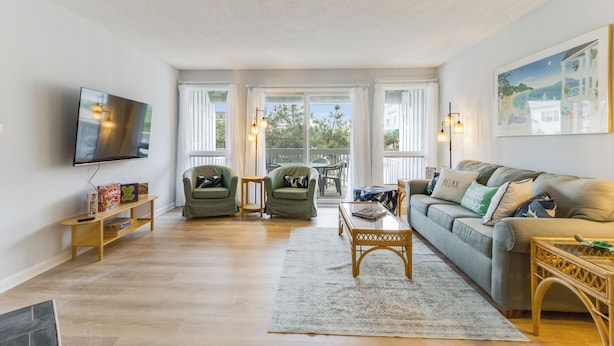 A living room with a sofa, two armchairs, a coffee table, a TV, and a bookshelf.