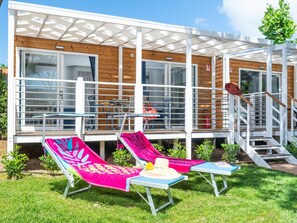 Un moderno espacio lounge al aire libre con dos tumbonas, una mesita y una escalera que da a una terraza de madera.