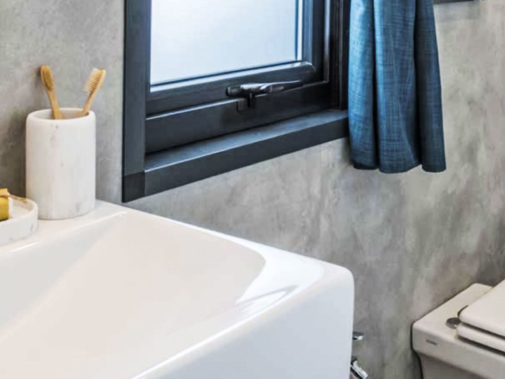 Une salle de bain moderne avec une baignoire blanche, des toilettes et une fenêtre avec un rideau.