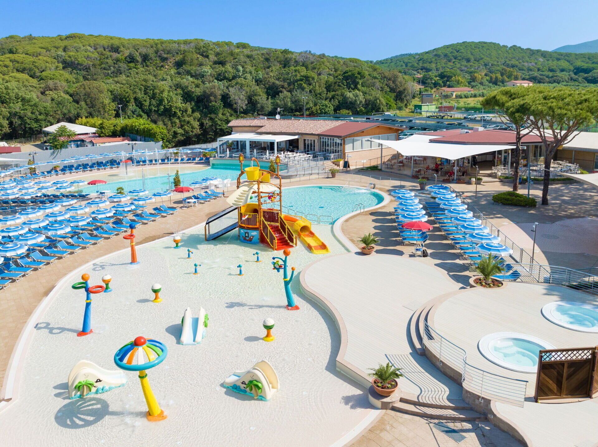 Un complexe hôtelier doté d’une grande piscine, d’un espace de jeux aquatiques et de nombreux chaises longues.
