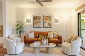 Ein Wohnzimmer mit einer Couch, zwei Sesseln, einem Couchtisch und Wandbildern.