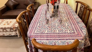 Una mesa de comedor con mantel estampado, rodeada de sillas de madera.