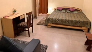 Un dormitorio con cama, escritorio, silla y una pequeña mesa.