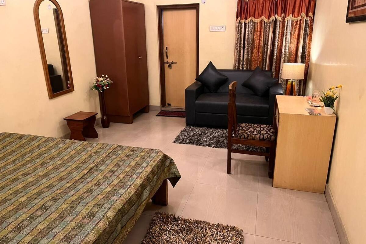 A room with a bed, a sofa, a desk, a wardrobe, and a mirror.