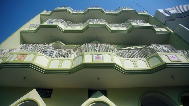 Un edificio de varios pisos con balcones, barandillas decorativas y una entrada central con un diseño geométrico.
