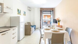 A modern kitchen with white cabinets, a refrigerator, and a dining area with a table set for four. - 1 bedroom awesome apartment in Alghero (Alghero)