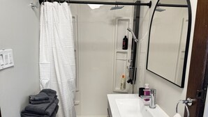 A compact bathroom with a shower, a sink, and a mirror. - Private Downtown Kitchener Studio | Parking, Kitchenette, Wi-Fi (Kitchener)