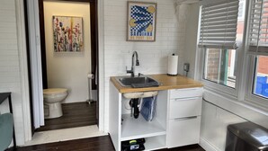 A compact kitchen with a wooden countertop, a sink, and a window with blinds. - Private Downtown Kitchener Studio | Parking, Kitchenette, Wi-Fi (Kitchener)