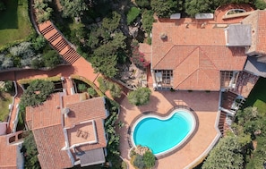 An aerial view of a property with a swimming pool, terracotta-tiled roofs, and landscaped gardens. - Lovely apartment in Porto Cervo with outdoor swimming pool (Porto Cervo)