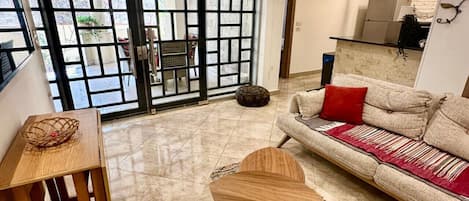 A living room with a sofa, a coffee table, a rug, and a dining table.