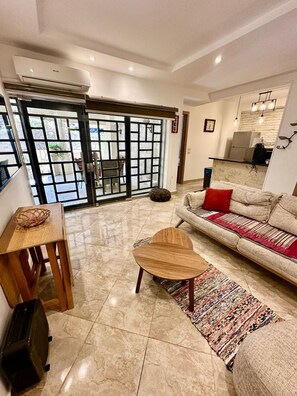 A living room with a sofa, a coffee table, a rug, and a dining table. - Elegant 2BR Heliopolis Suite | Private Garden Terrace & A/C (Heliopolis)