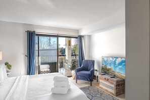 Ein Hotelzimmer mit Bett, Sessel, Fernseher und einem Balkon mit Blick.