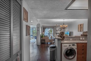 A modern kitchen with a built-in washing machine, a chandelier, and a dining area with a view. - Sea Mark Tower Unit 204 (Myrtle Beach)