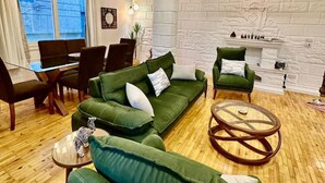 En moderne stue med en grøn sofa, et rundt sofabord og en pejs.
