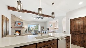 Une cuisine moderne dotée d’un grand îlot central, de meubles en bois et de luminaires suspendus.