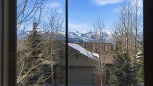 Un quartier résidentiel avec une maison au premier plan et des montagnes enneigées en arrière-plan.