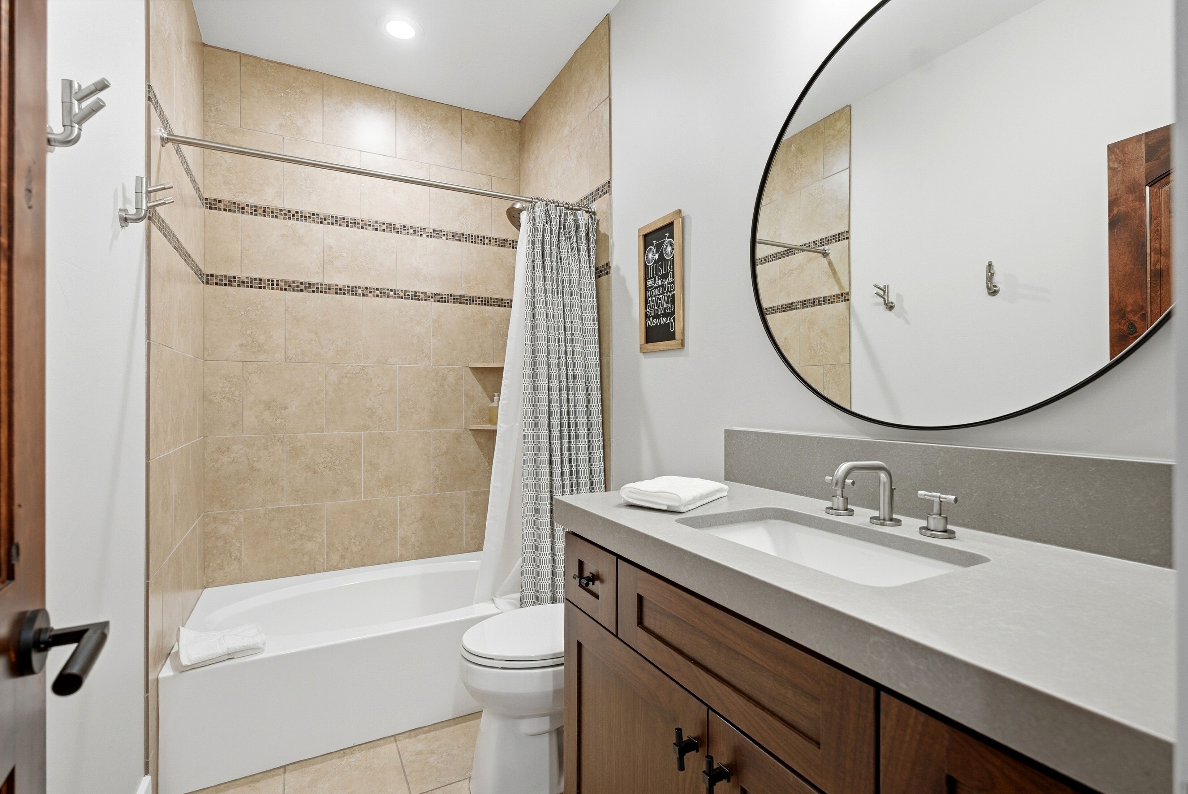 A modern bathroom with a bathtub, toilet, and vanity.