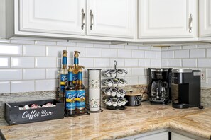 A kitchen with white cabinets, a coffee bar, and various coffee-making equipment. - Steps to Belmont Shore Retreat - Firepit - Games - Near DTLB! (Long Beach)