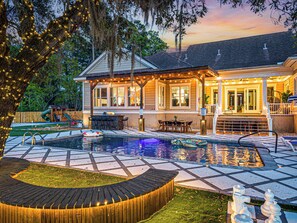 A house with a swimming pool, outdoor seating, and string lights.