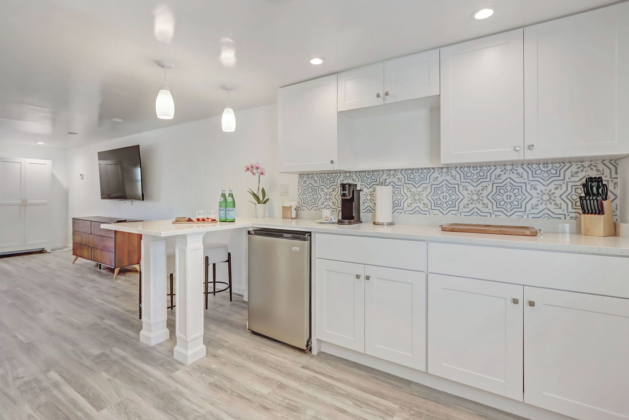 A modern kitchen with white cabinetry, a stainless steel dishwasher, and a patterned backsplash.
