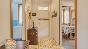 A hallway with a patterned floor, a wooden cabinet, a door with a handle, and a window with curtains. - C Marinaio-vista mare e centro (Recco)