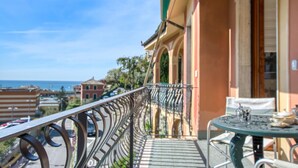 A balcony with a metal railing, a table with chairs, and a view of the sea and buildings. - C Marinaio-vista mare e centro (Recco)