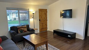 Ein Wohnzimmer mit Sofa, Couchtisch, Fernseher und einer Holztür.