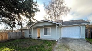 Ein eingeschossiges Haus mit Veranda, Garage und gepflegtem Rasen.