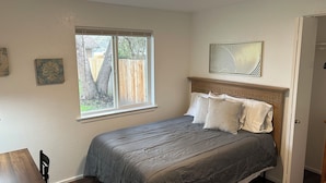 Ein Schlafzimmer mit Bett, Fenster, Tür und einem kleinen Tisch.