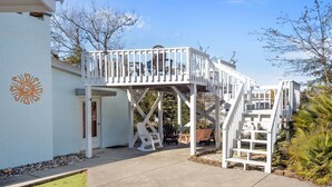 Un edificio blanco con un patio cubierto, una terraza blanca y una escalera que conduce a un segundo nivel.
