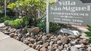 Señal de los condominios Villa São Miguel, con números de contacto y dirección.