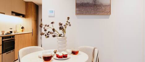 Una cocina moderna con armarios de madera, una mesa de comedor con sillas y un florero con flores secas.