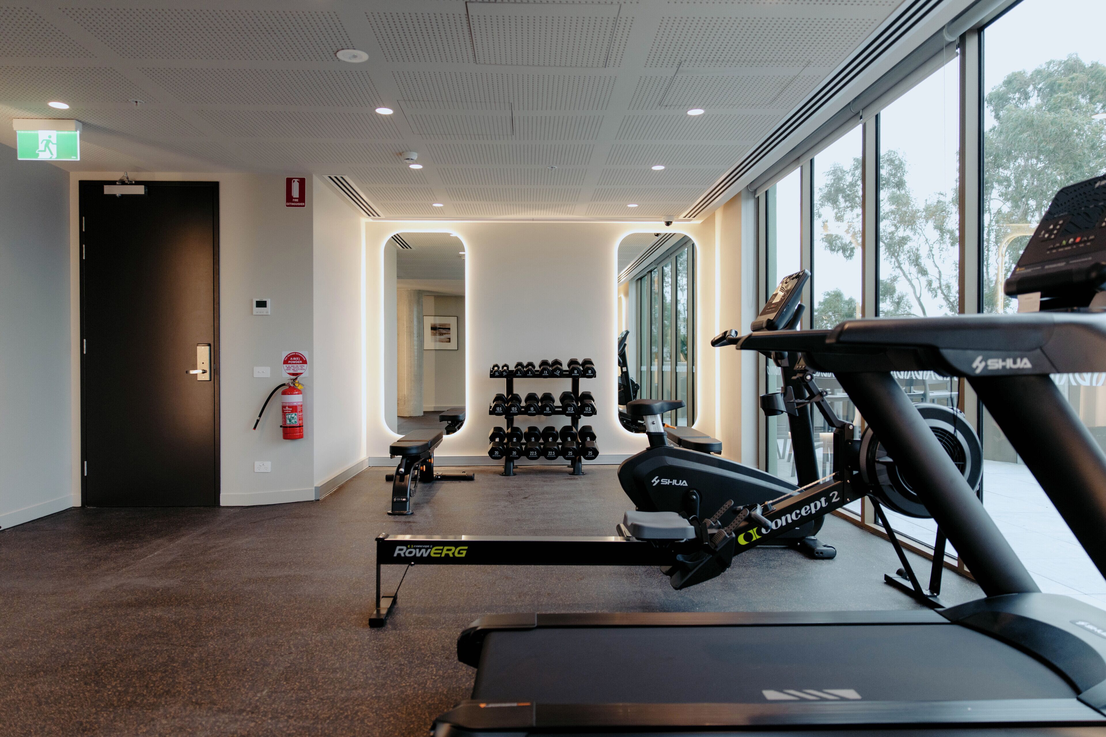 Et fitnesscenter med løbebånd, håndvægte og en romaskine.