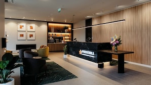 A modern reception area with a marble counter, seating, and a wooden wall.