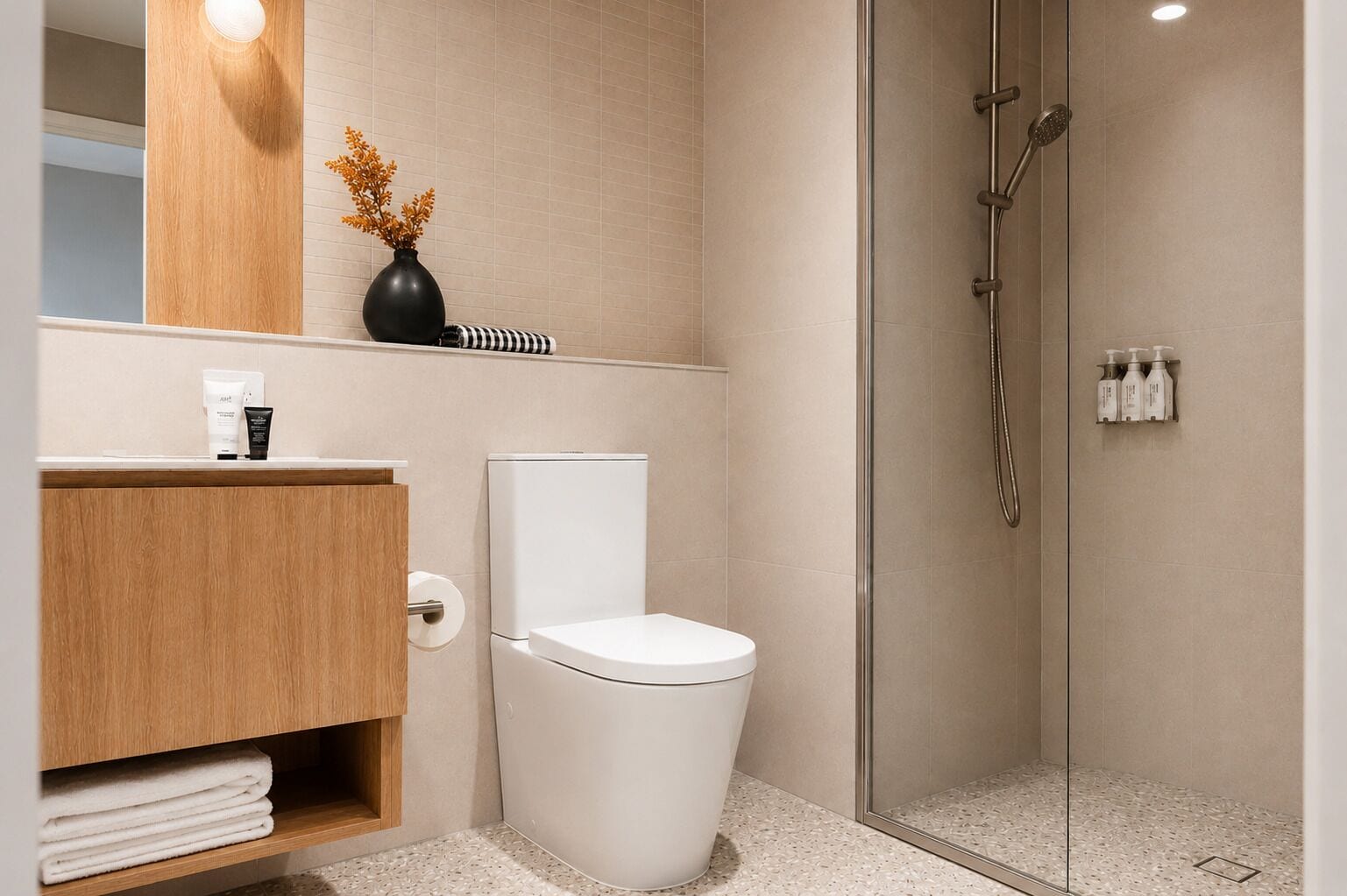 Ein modernes Badezimmer mit Toilette, Dusche und Waschtisch mit Toilettenartikeln.
