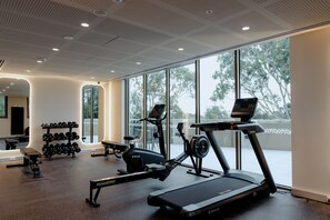 A gym with exercise equipment, large windows, and a ceiling with recessed lighting. - Punthill Epping (Epping)