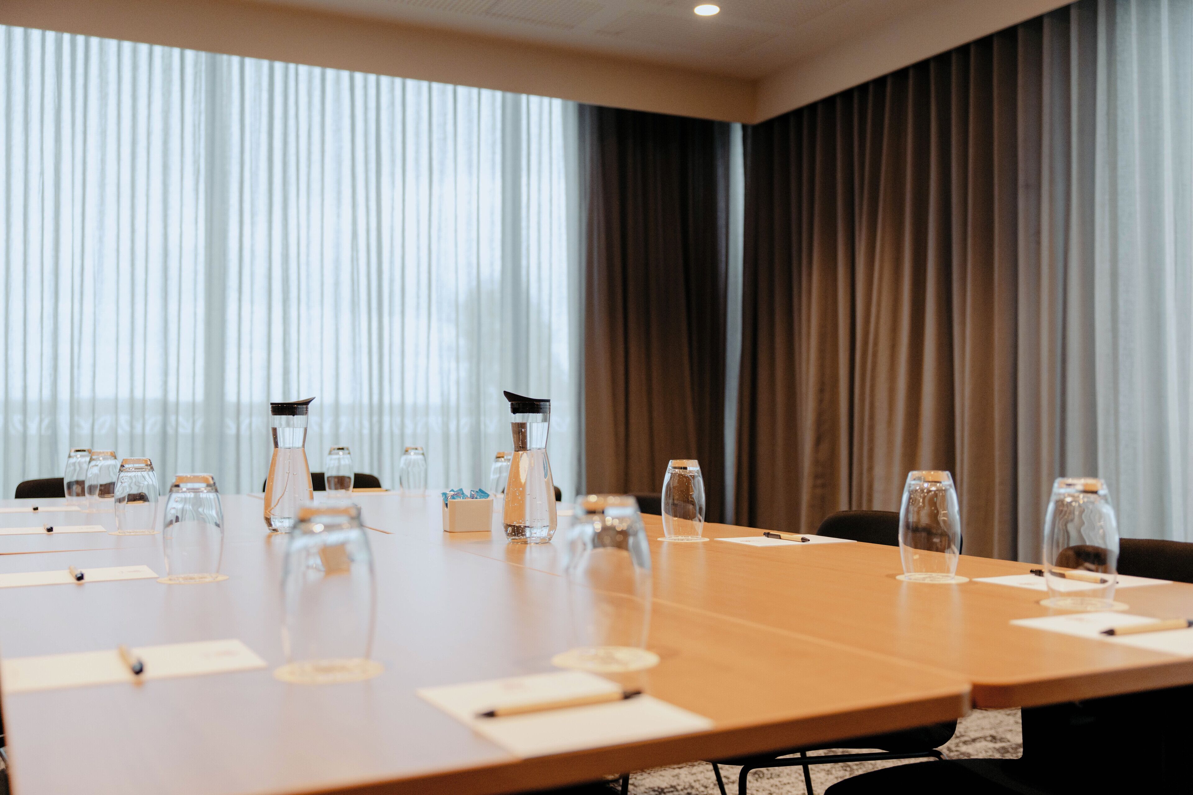 A conference room with a long table, chairs, and glassware.