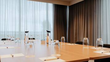 Une salle de conférence avec une longue table, des chaises et de la verrerie.