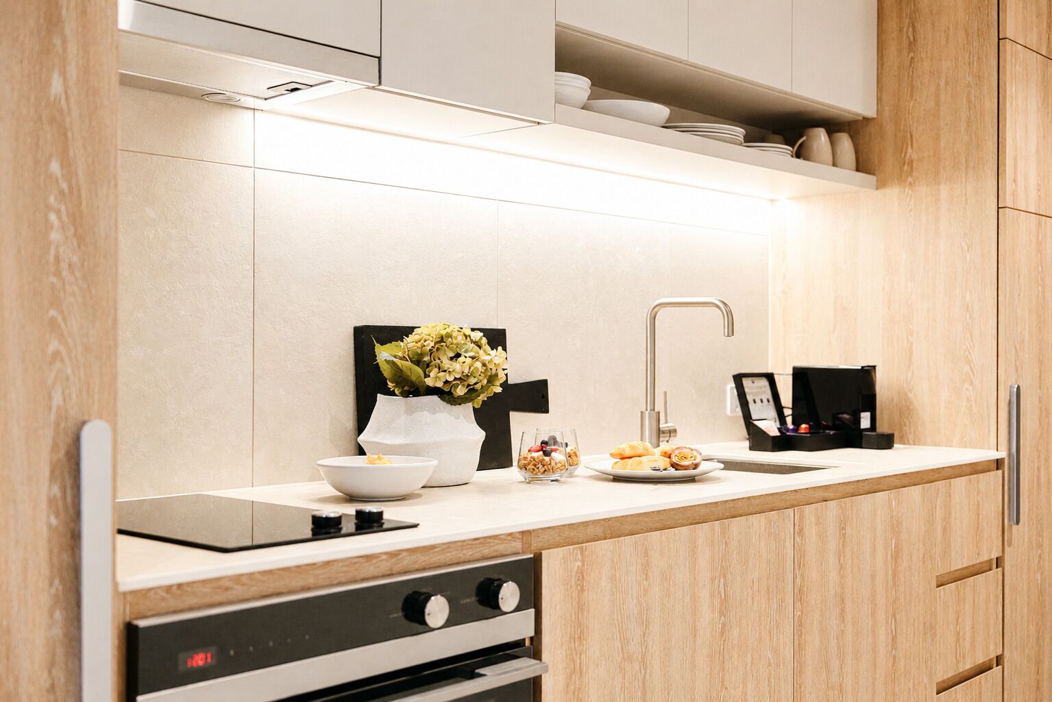 A modern kitchen with a built-in oven, a sink, and a coffee machine.