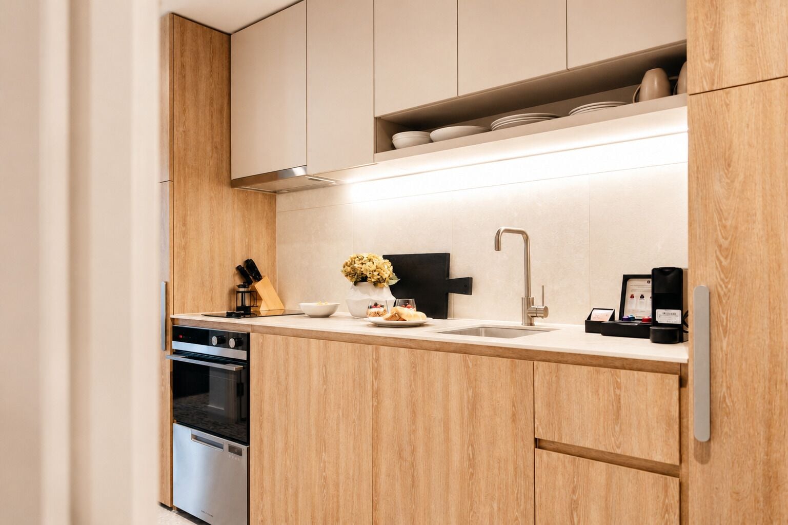 Une cuisine moderne avec des meubles en bois, un évier en acier inoxydable et un four encastré.