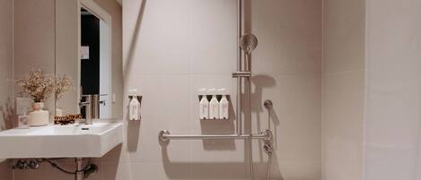 A modern bathroom with a sink, mirror, shower, and toiletries.