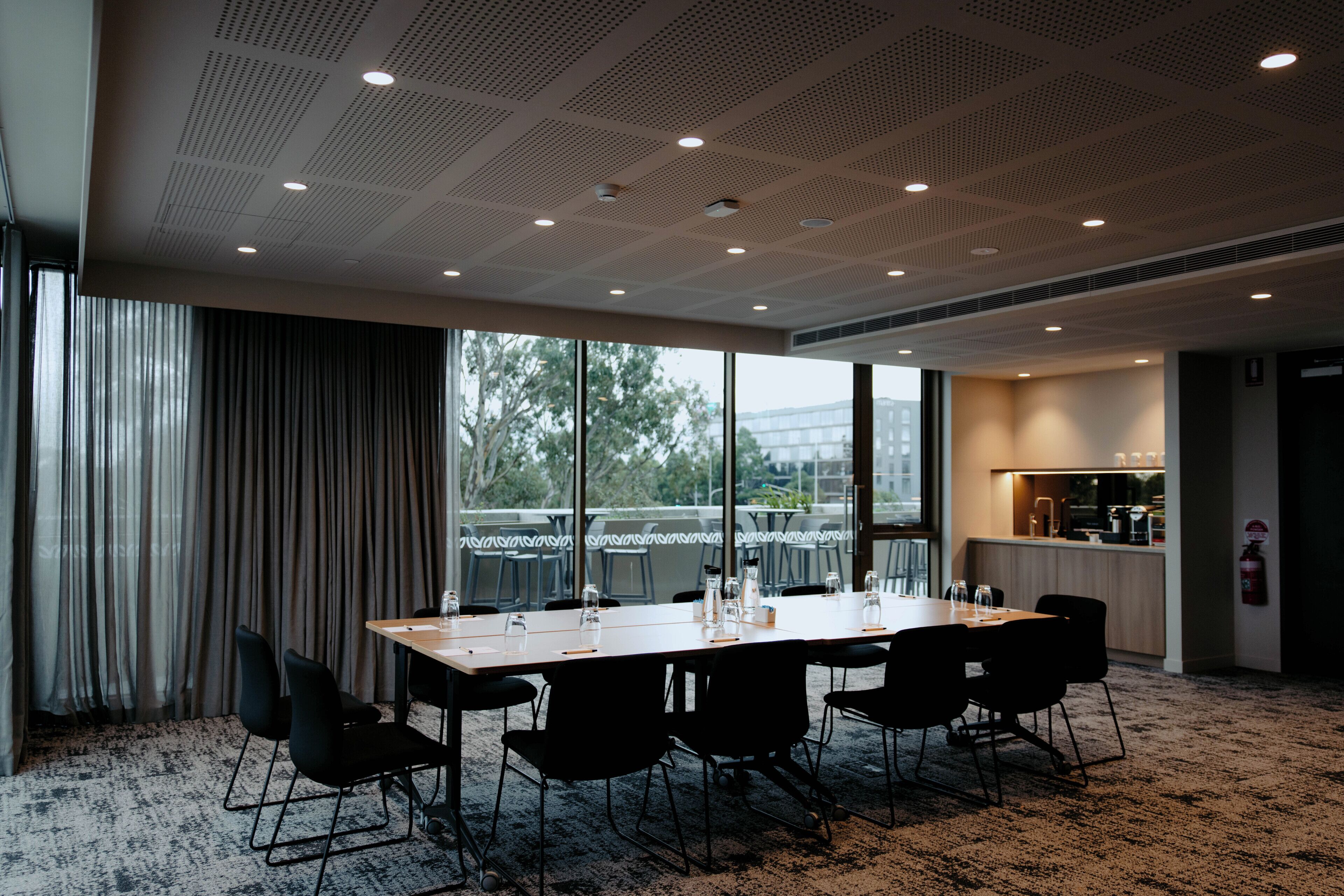 A conference room with a long table, black chairs, and large windows.