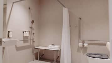 Een badkamer met douche, toilet, wastafel en een bankje met handdoeken.