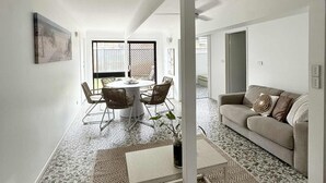 Amplia sala de estar con una mesa de comedor, sillas, un sofá y un tapete estampado.