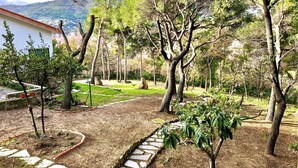 Ein Garten mit Kieswegen, Bäumen und einer Steinmauer.