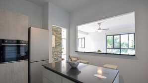 Eine moderne Küche mit Einbauofen, einer Wand mit Steinverkleidung und einem Fenster mit Blick auf Grünflächen.