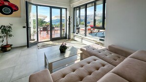 Ein geräumiges Wohnzimmer mit einem großen Schiebeglastür, die auf eine Terrasse im Freien führt.