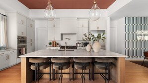 A modern kitchen with a large island, bar stools, and pendant lighting. - Cactus Cove - Luxe Adventures by Hello Hideout (Austin)